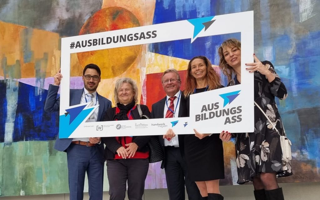 Vier Personen halten Rahmen und stehen vor abstraktem Gemälde