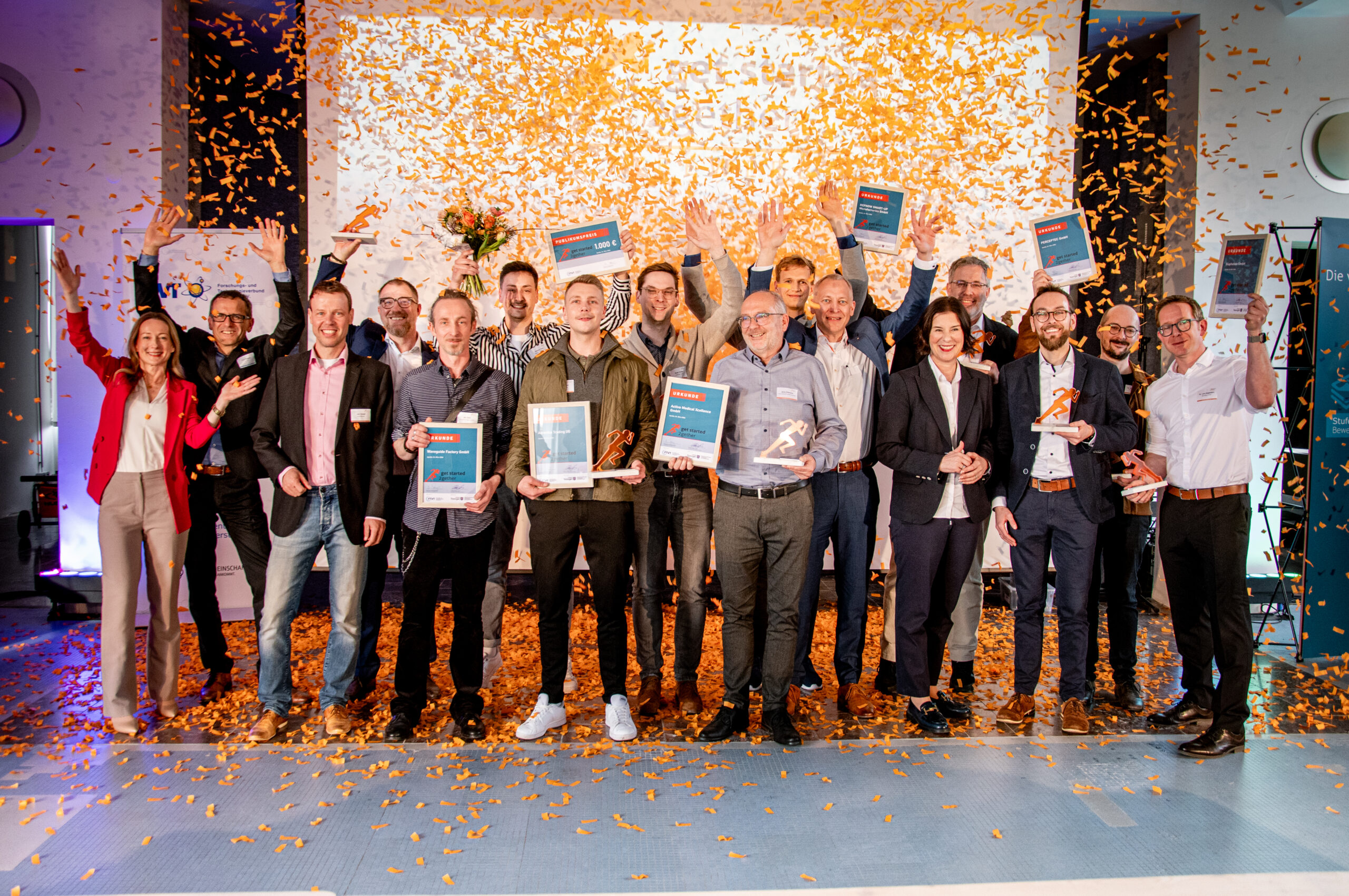 Personen Benjamin Redlingshöfer und Preisträgerin Cosima Richardson geben sich ein High-Five und überreichen Geldpreis auf dem get started 2gether Gründerwettbewerb